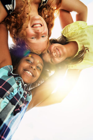 Our special circle of friends. Portrait of a group of diverse and happy kids huddled together on a bright day outside.の写真素材