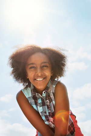 What a great day to be outside. Portrait of a happy girl standing outside on a bright summers day.の写真素材