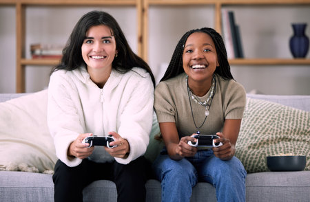 Friends, women on sofa and video games for quality time, relax or happiness on break, competitive or multiplayer app. Female gamers, ladies or controllers for esports, fun or entertainment with smileの写真素材