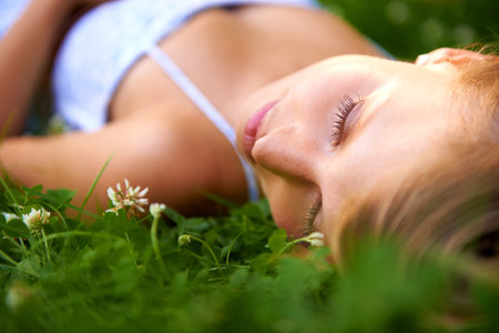 Sleeping beauty. an attractive young woman lying on the grass with her eyes closed.の写真素材