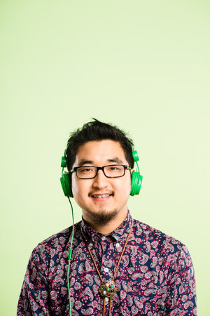 Im not me without music. a handsome young man standing alone in the studio and listening to music through headphones.の写真素材
