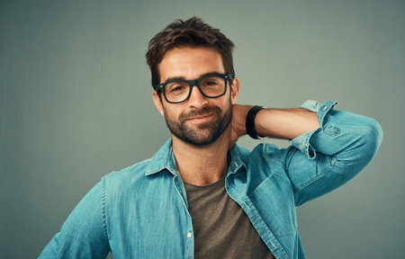 Cool and casual is the way to go. Studio portrait of a handsome young man posing against a grey background.の写真素材