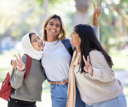 Women, friends or peace sign in nature park, garden or school campus for diversity bonding, comic fun or playful community. Smile, happy or Muslim students and v hands gesture on university collegeの写真素材