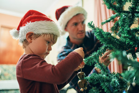 Everybodys favourite Christmas tradition. an adorable little boy decorating the Christmas tree with his father at home.の写真素材