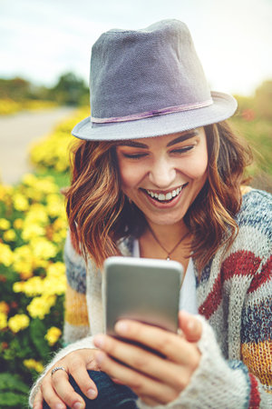 Inviting someone to join her on a beautiful day outdoors. an attractive young woman using a mobile...