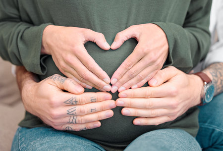 Parenting is a hands-on job. Cropped shot of an unrecognizable couple sitting with their hands on the expectant mothers belly.の写真素材