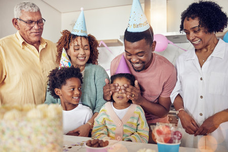 Birthday, party and surprise with family in kitchen for celebration, bonding and affectionate. Happiness, excited and care with parents and child at home for generations, fun and special eventの写真素材