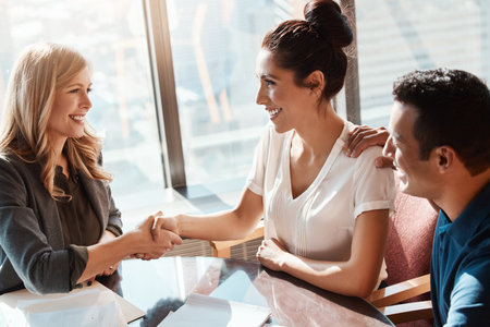Their financial future is kind of a big deal. a young couple meeting with a financial planner in a modern office.の写真素材