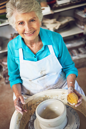 Working with my hands brings me so much happiness. Portrait of a senior woman making a ceramic pot in a workshop.の写真素材