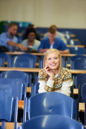 Shes ahead of the curve. Portrait of a smiling college student sitting in a lecture hall.の写真素材