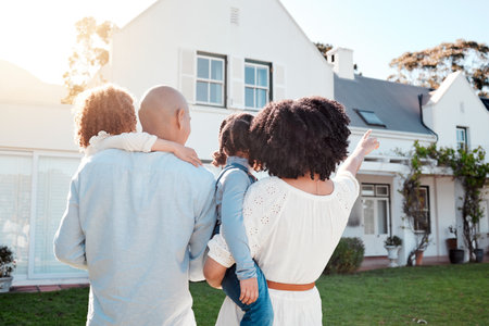 Real estate, love and family in the yard of their new house bonding and spending quality time together. Mortgage, luxury property and back of young mom, dad and children standing by their modern homeの写真素材