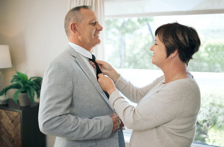 Will you straighten my tie please. a mature woman helping her husband fix his tie.の写真素材