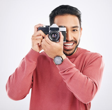 Happy, photographer and portrait of Asian man with a camera isolated on a white background in studio. Smile, work and a Japanese journalist in photography taking pictures for the media or paparazziの写真素材