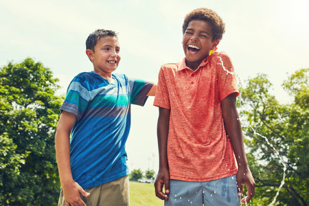 What the holidays is all about. adorable young boys playing with water balloons outdoors.の写真素材