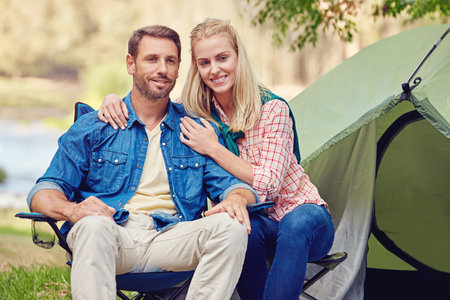 In love out in nature. Portrait of an affectionate couple camping out in the woods.の写真素材