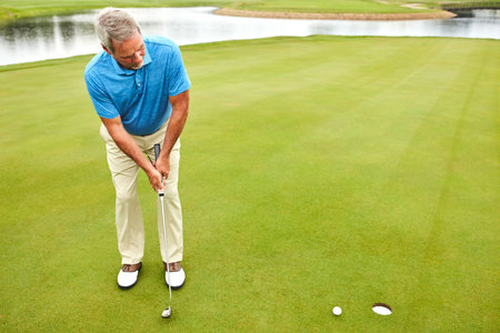 Comfortable on and around the green. a mature man out playing golf in his free time.の写真素材
