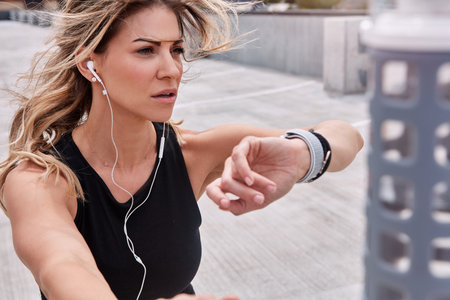 Getting closer to her goals with every second. a sporty young woman checking her watch while...