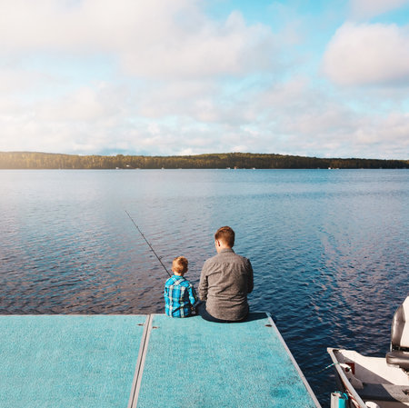 Doing what boys love to do. a father and his young son out fishing by the lake.の写真素材