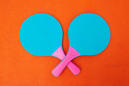 You dare challenge me. High angle shot of two table tennis bats placed together on top of an orange background inside of a studio.の写真素材