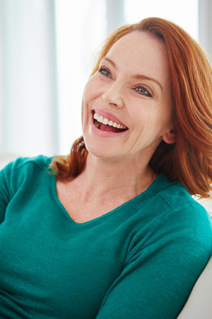 Shes having a laugh. a mature woman relaxing on the sofa at home.の写真素材