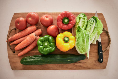 Vegetables, cutting board and healthy food on the counter in the kitchen for a vegan meal. Crops,...