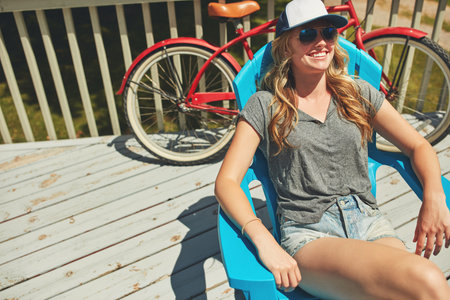 If youre looking for me, Ill be chilling out here. an attractive young woman relaxing on a deck chair outdoors.の写真素材