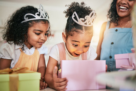 Girl child, box and wow for gift, surprise or happiness for princess at birthday in family home. Female kid, present and smile with mother, sister and happy at party with tiara, love or bond in houseの写真素材