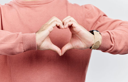 Heart, man and hands for love in studio to show support, thank you or charity sign language. Male model person with hand icon for kindness, care and hope review, motivation or emoji opinion feedbackの写真素材