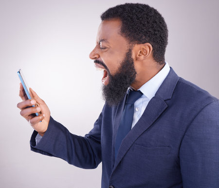 Business black man, angry phone call and studio with bad deal, mistake and frustrated by white background. Corporate, african businessman and smartphone for shouting with anger, stress and anxietyの写真素材