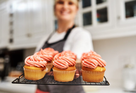 Theres always a market for yummy baked goods. a woman holding freshly baked cupcakes in her kitchen...