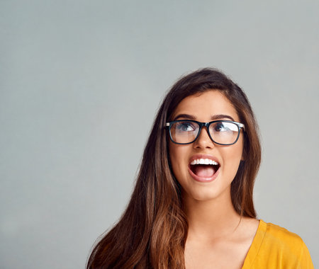 Wow, would you look at that. Studio shot of an attractive young woman looking surprised against a grey background.の写真素材