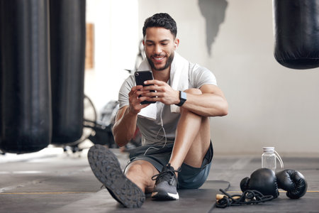Fitness, man with smartphone and earphones at the gym happy for training or health wellness. Meditation or commitment, exercise or workout and male athlete listen to music or podcast for motivationの写真素材