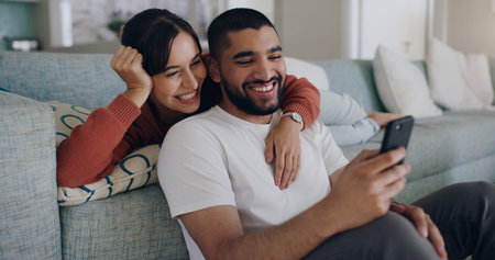 Couple, phone and laughing at meme on social media or internet joke and relax in a living room couch...