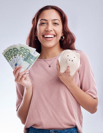 Money, portrait or happy girl with a piggy bank for financial wealth or savings on white background. Finance, investment or woman smiling or investing Euros or budget in tin for safety or securityの写真素材