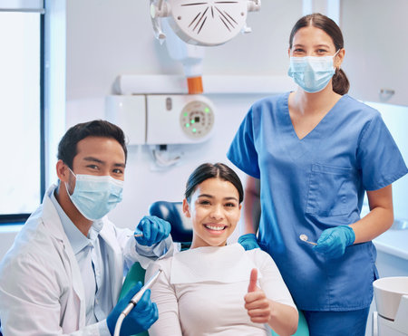 Portrait of dentist, thumbs up and patient in consultation for teeth whitening, service and dental care. Orthodontist, dentistry and woman with thank you sign for oral hygiene, healthcare or cleaningの写真素材
