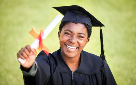 Portrait, graduation or degree with a student black woman on university campus at a scholarship event. Education, smile or diploma with a happy female pupil standing outdoor as a college graduateの写真素材