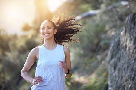 Happy woman, running and smile in forest for fitness, workout or cardio exercise in the outdoors....