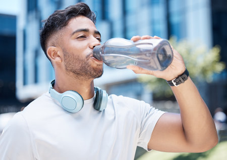 Man, fitness and drinking water in city exercise, cardio workout or running for sustainability outdoors. Thirsty male person, athlete or runner with drink for hydration, rest or break in urban townの写真素材