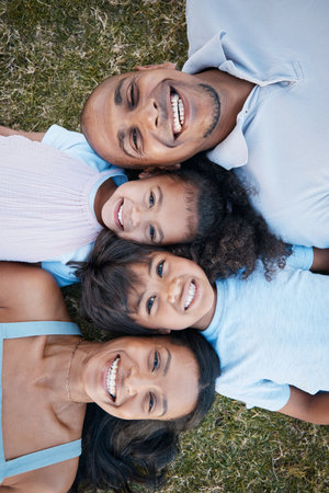 Family, portrait and lying on grass in garden with mother, father and kids together with love. Face, top view and dad with mom and children with parent support and care on a lawn with happy smileの写真素材