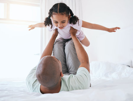 Airplane, playful and father with daughter in bedroom for morning, wake up and weekend. Happy, excited and funny with man and young girl playing in family home for happiness, freedom and supportの写真素材