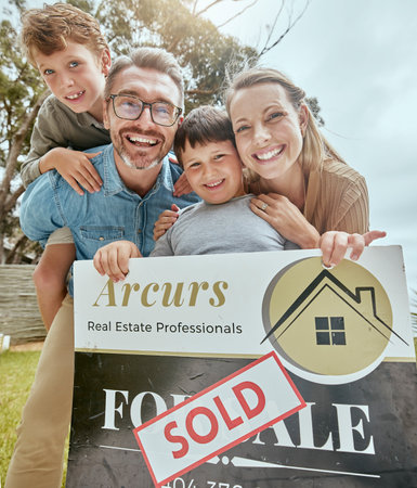 Parents, kids and real estate sale with poster, portrait and smile for new home, start and investment for future. Father, mother and boy children with sold sign, property investing and family houseの写真素材