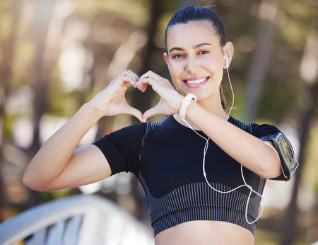 Runner, heart hands or portrait of happy woman in park for running exercise or workout for body health. Love sign, hand gesture or active girl athlete runner in sports training for fitness in natureの写真素材