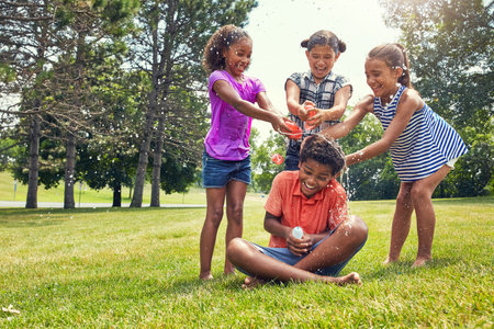 We have taken him captive. adorable children playing with water balloons outdoors.の写真素材