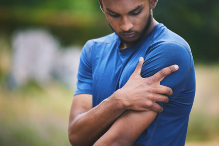 Sports, fitness and man with pain in shoulder after workout, exercise and marathon training outdoors. Medical emergency, health and male person with muscle strain, arm injury and joint ache in parkの写真素材