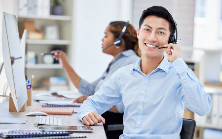 Portrait, call center and Asian man smile for customer service, telemarketing or tech support. Face, crm and sales agent, consultant or employee coworking at help desk, business office and consultingの写真素材