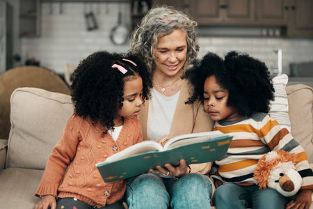 Family children, book and grandma reading fantasy storybook, story or bond on home living room sofa. Love, grandma babysitting and elderly woman with child development for biracial kindergarten kidsの写真素材
