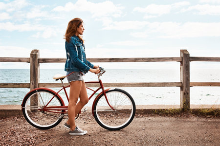 Fitness is a lifestyle. a beautiful young woman with her bicycle on the promenade.の写真素材