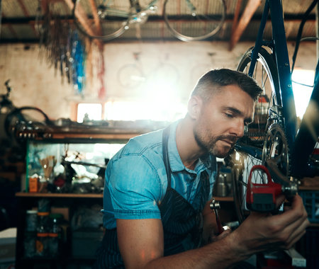 Devoting time and attention to every bike. a mature man working in a bicycle repair shop.の写真素材