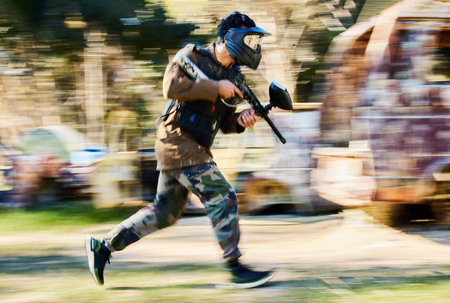 Fast, running and paintball man, gun and outdoor battlefield, playground or games in forest adventure training. Shooting skill, player or sports person with military speed, action and target missionの写真素材