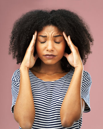 This is too much for me. a young woman suffering from a headache against a pink background.の写真素材